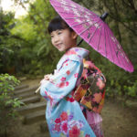七五三7歳女の子ガーデンフォト傘をさして 優しく微笑む