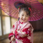 和傘を持って笑うアンティークな着物を着た３歳女の子