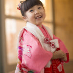 笑顔で見つめる白い被布ピンクの着物を着た３歳女の子